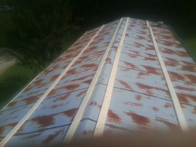 Rusted metal roof panels with new wood purlins before replacement — Storm Damage Roof Repair in Jacobsburg by Roofing Brothers