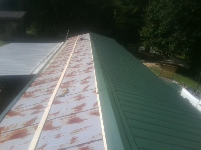 Old rusted panels beside newly installed green metal roofing — Wind Damage Roof Repair by Roofing Brothers in Jacobsburg