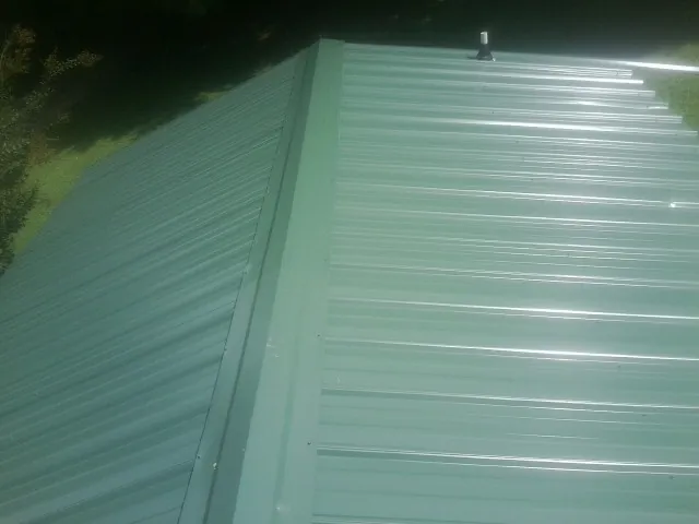 New green metal panels meeting at the ridge of a roof — Flat Roof Repair work by our crew in Jacobsburg