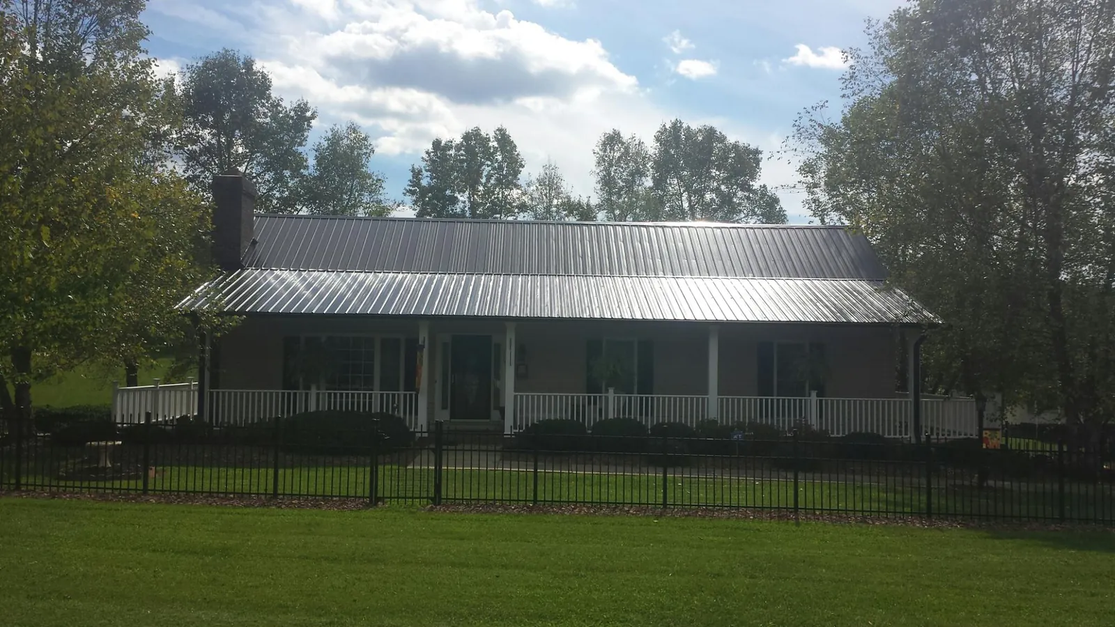 Gray metal roof on a brick ranch with a full width front porch — Gutter Guard Installation work by our crew in Jacobsburg
