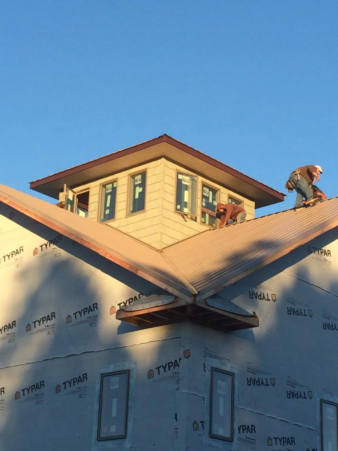 Roofers working around a rooftop cupola on a new metal roof at sunset — Roof Waterproofing in Jacobsburg by Roofing Brothers